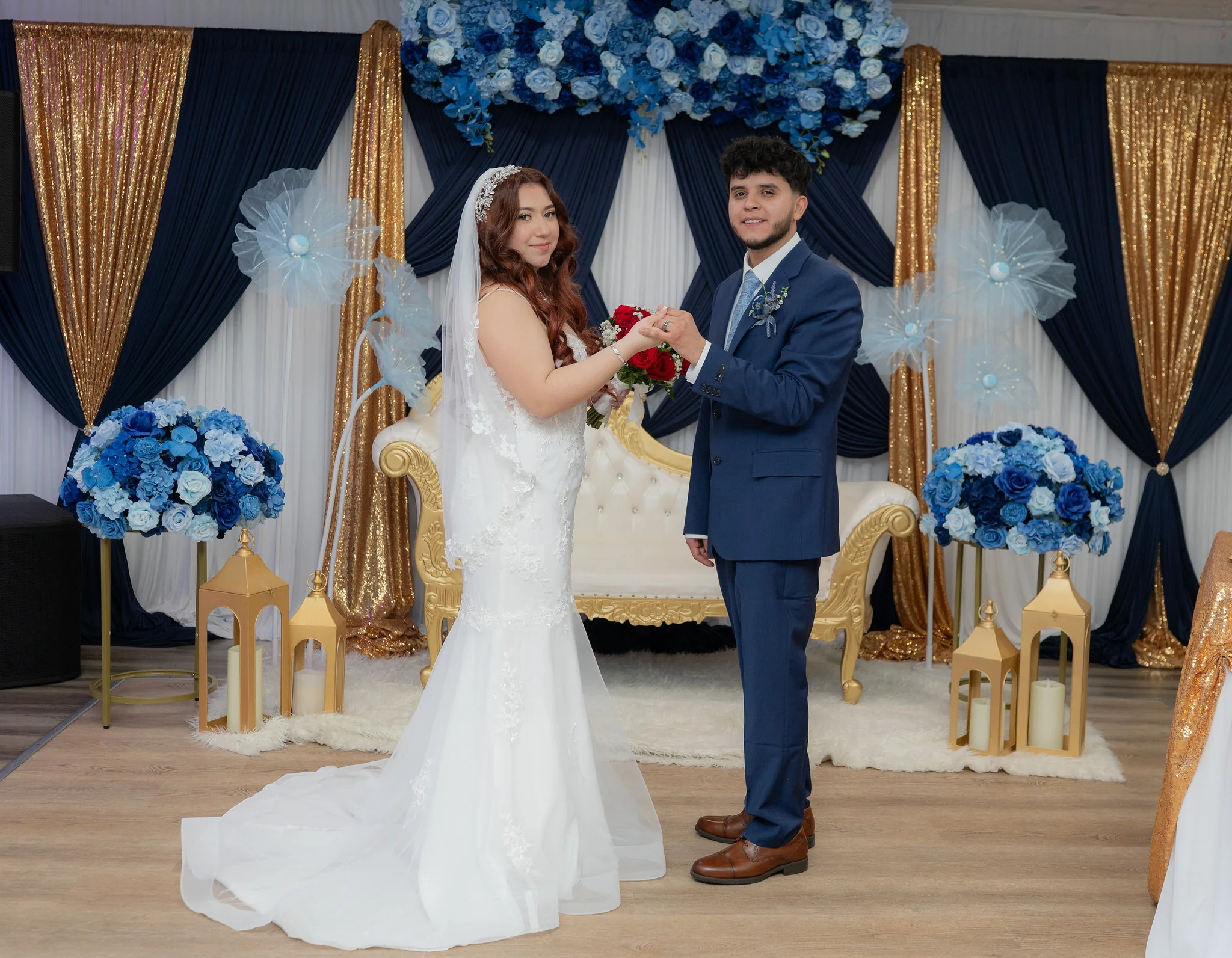 Wedding couple posed in front of a blue and gold Los Olivos event backdrop